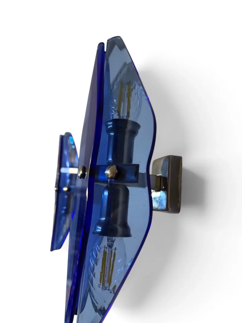 Side view of a VECA wall sconce with faceted blue glass and brass crossbar, showing two visible sockets