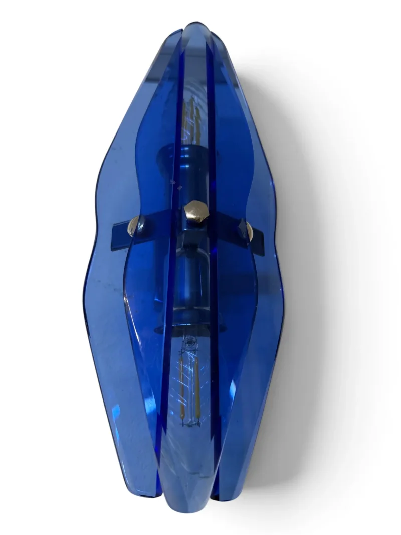 Top-down view of a VECA wall sconce showing the blade-shaped silhouette of the faceted blue glass