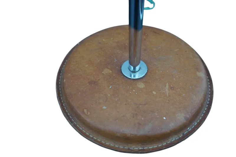 Close-up of the round tan leather base with white stitching and chrome stem of the Simris lamp
