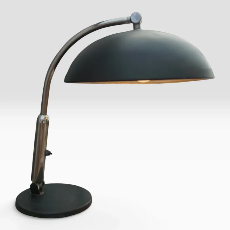 Hala Zeist model 144 desk lamp switched on, showing the dome shade glowing above the curved chrome arm