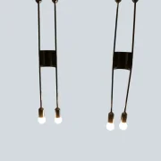 Front view of two illuminated Cosack 4166 wall sconces, showing the curved chrome connector and four glowing bulbs